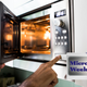 hands pressing buttons on a microwave